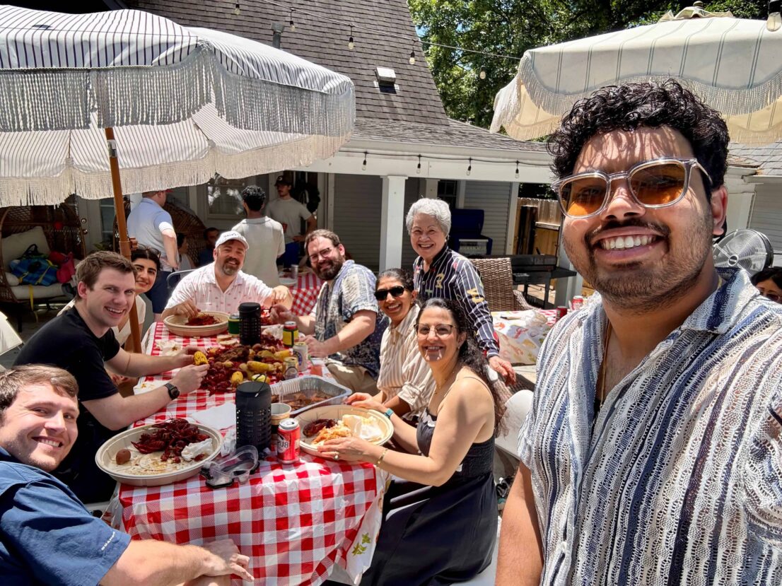 People sitting outside under an table with an umbrella.