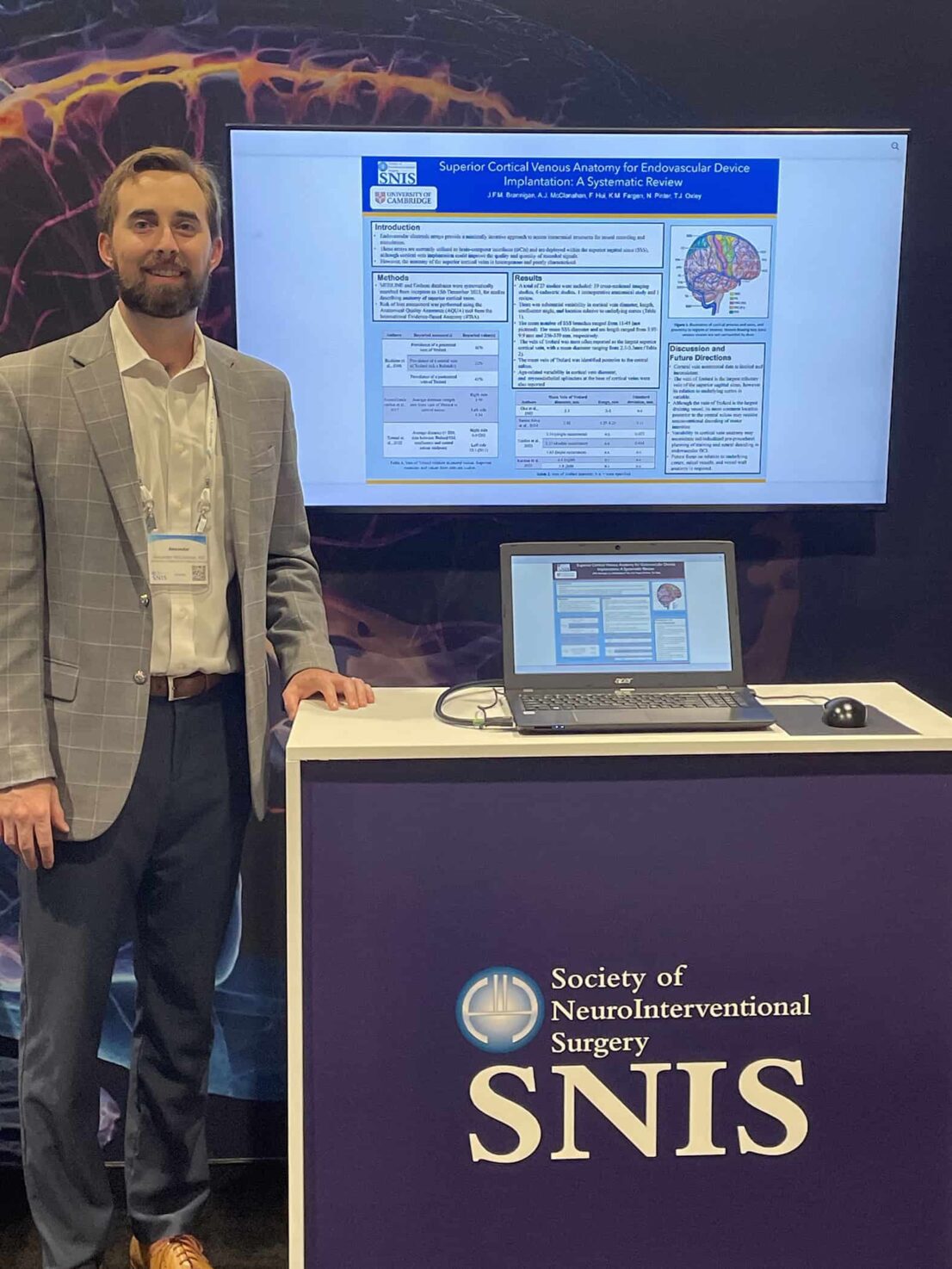 Alex McClanahan standing next to his poster presentation at SNIS.