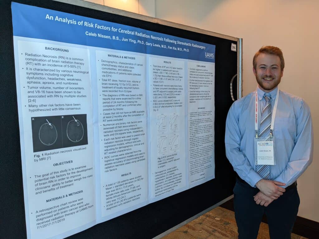 Medical Student, Caleb Nissen, stands before his abstract on his research at ACRO