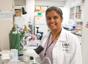 Nirmala Parajuli, Ph.D., posing with a microscope in her lab.