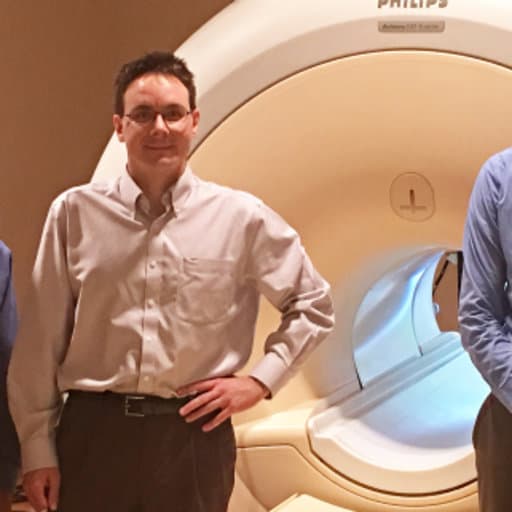 Dr. Andrew James standing next to an MRI machine