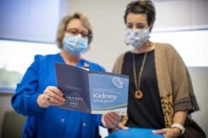 Two women in exam room, wearing masks, looking at a brochure