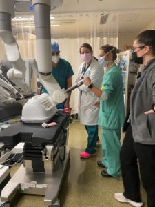 faculty member discusses the robotic system with a group of residents at bedside