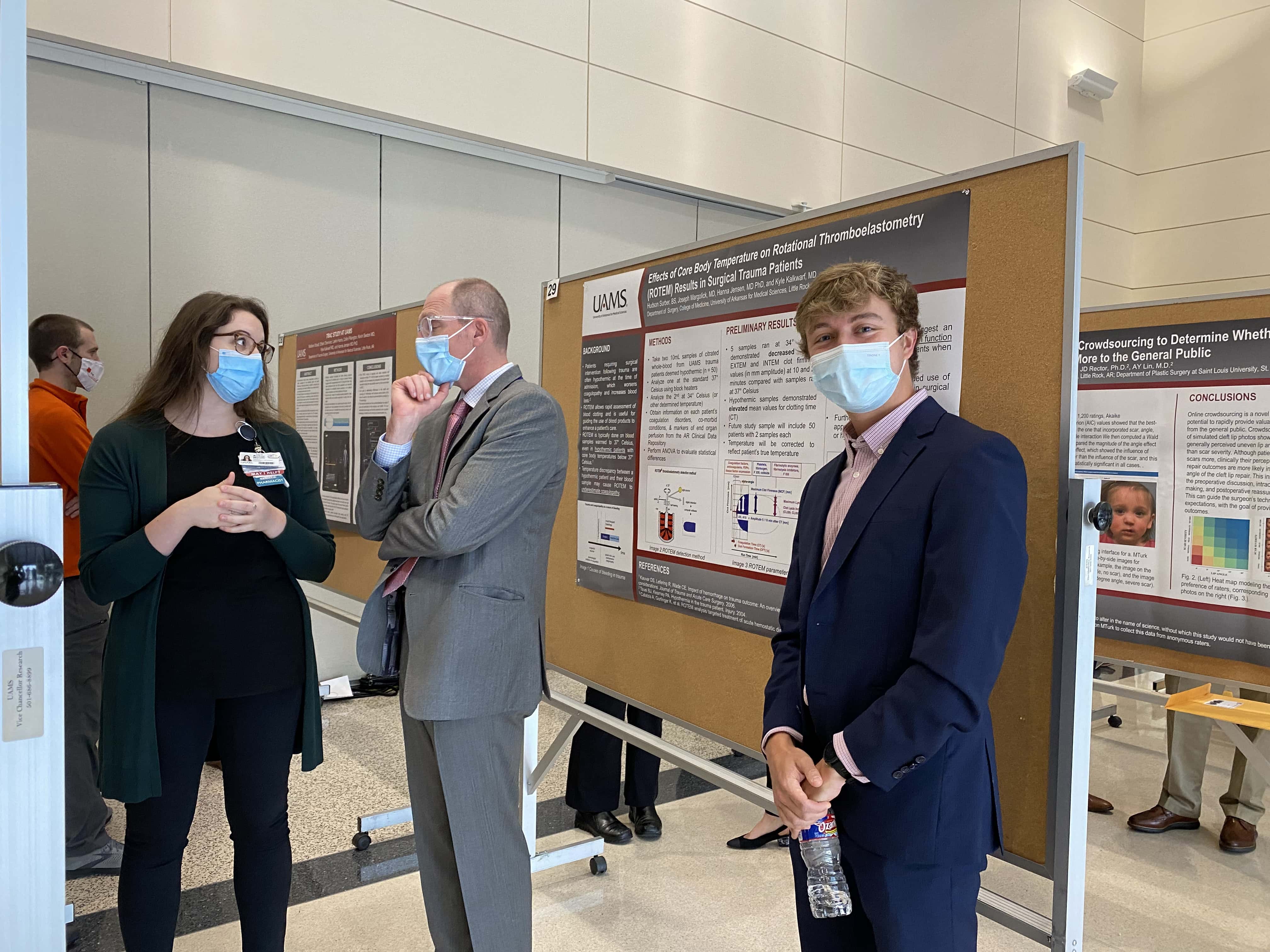 Student poses for the camera in front of a research poster