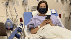 Woman in a hospital bed wearing a mask