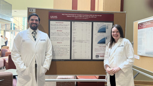 two residents stand in front of a their research poster