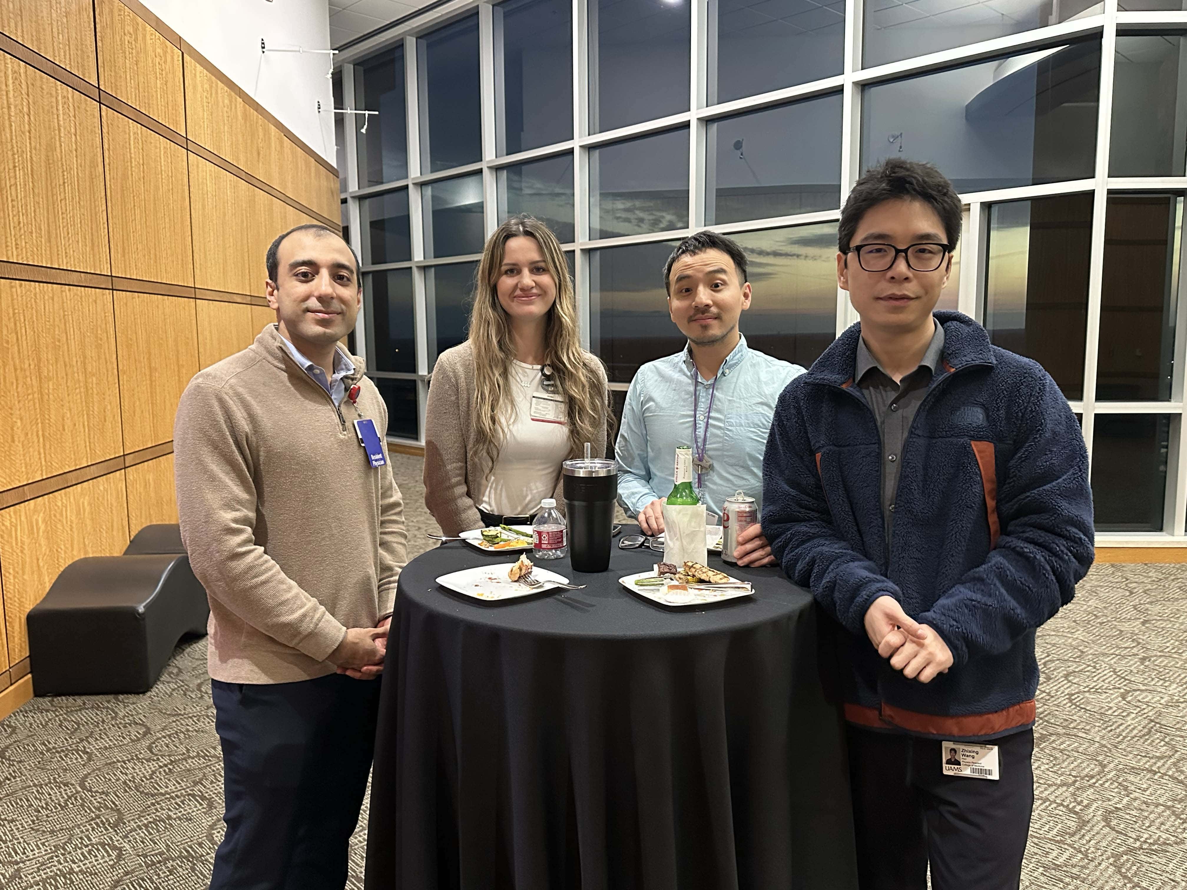 Group of faculty posing around a small table at a reception