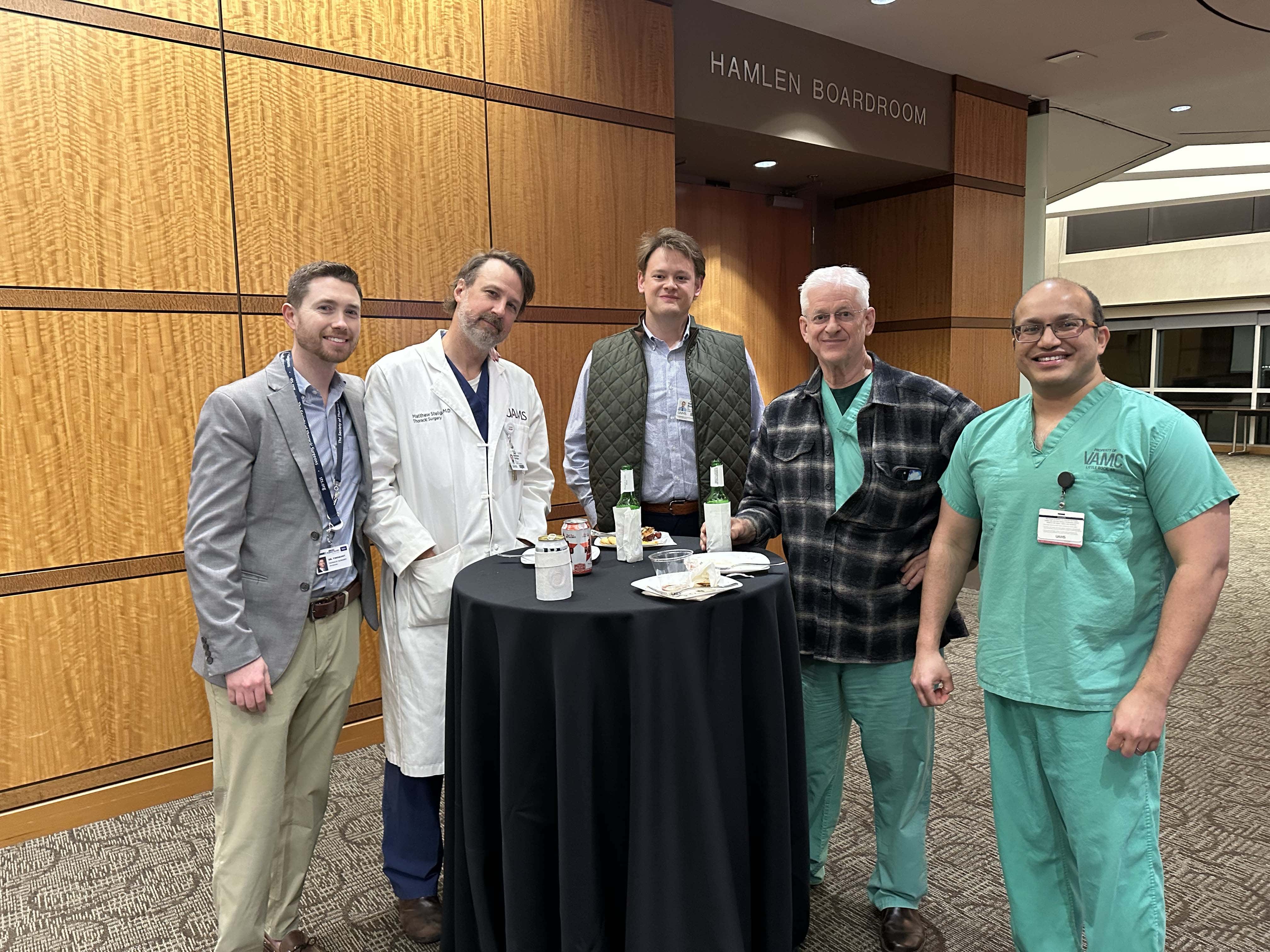 Group of faculty members posing around a table at a reception