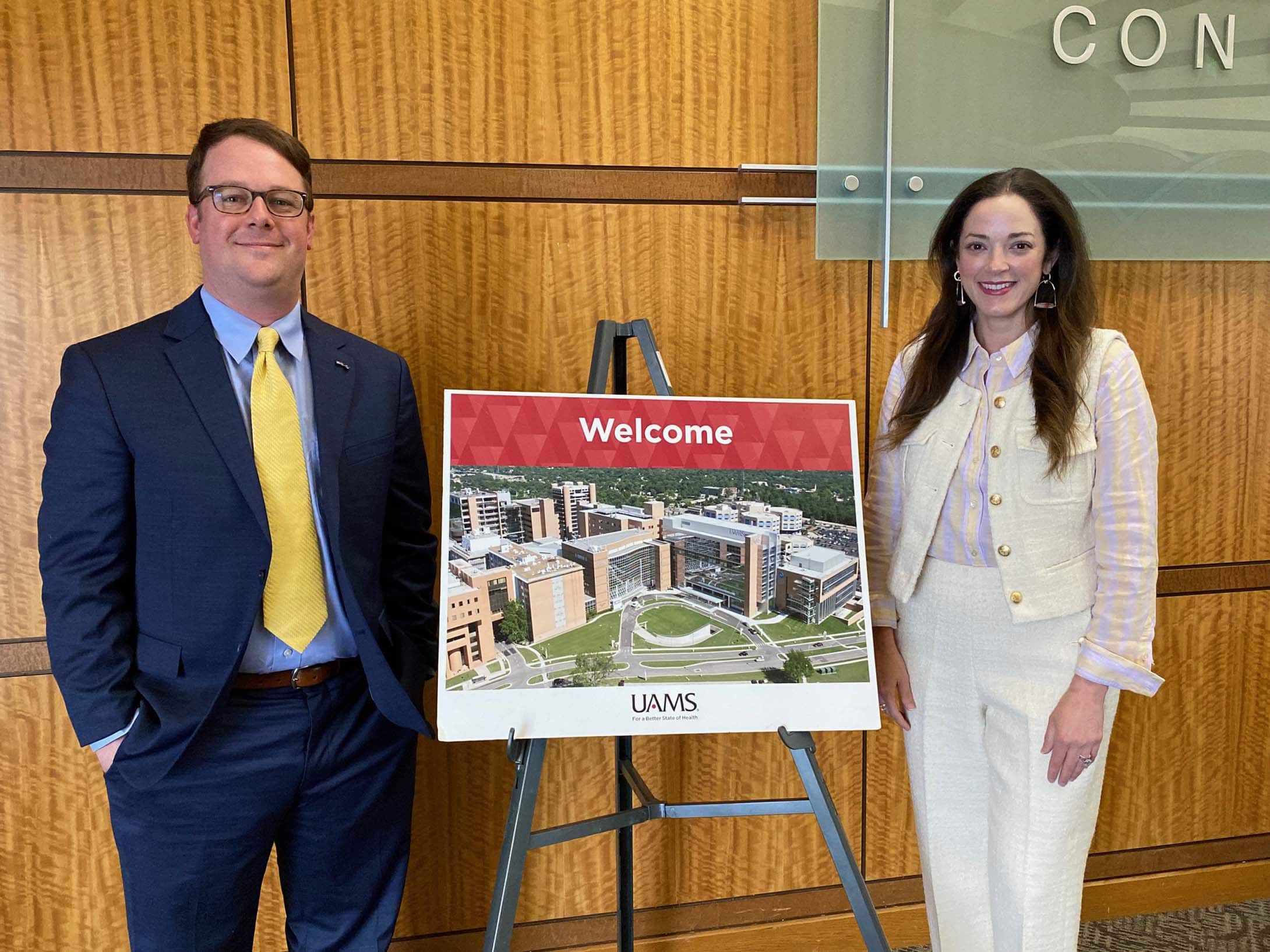 Two people standing in front of a welcome sign