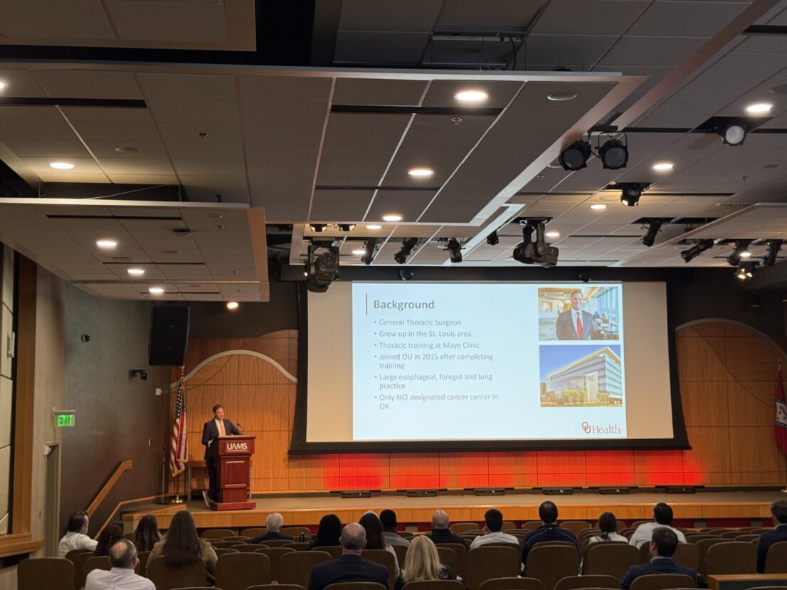 Guest speaker at the lectern while information in on a large screen next to him