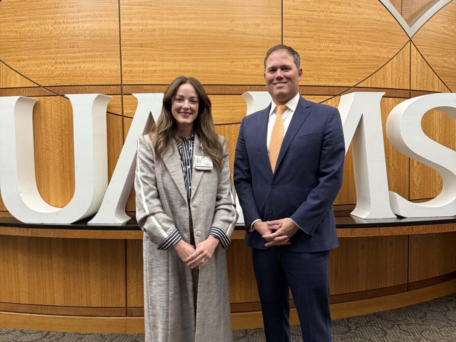 two people standing in front of a UAMS sign