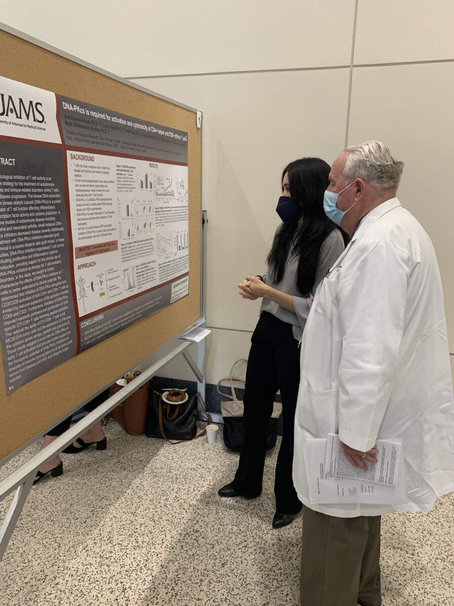 student shows a research poster to a faculty member