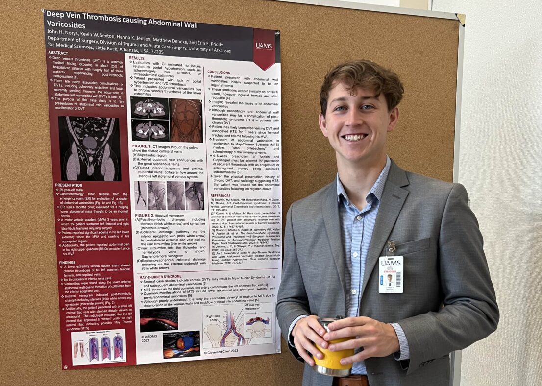 Student poses next to his research poster