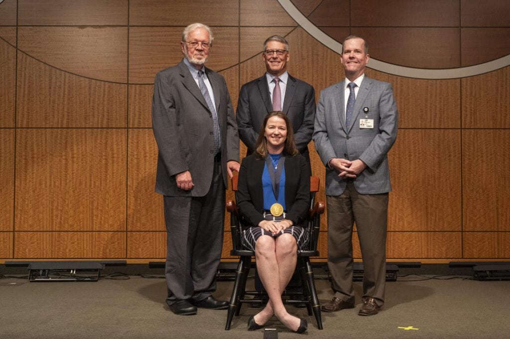 The University of Arkansas for Medical Sciences (UAMS) invested Julie Riley, M.D., (seated) in the Hal Reed Black, M.D., Chair in Urology. (Standing from left) G. Richard Smith, M.D., interim dean of the College of Medicine and UAMS executive vice chancellor; Timothy Langford, M.D., chair of the Department of Urology; and Cam Patterson, M.D., MBA, UAMS chancellor and CEO of UAMS Health.