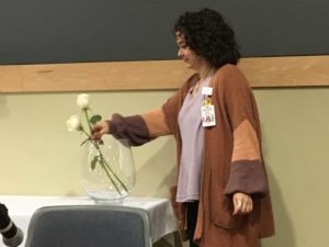 Student puts a white rose into a vase
