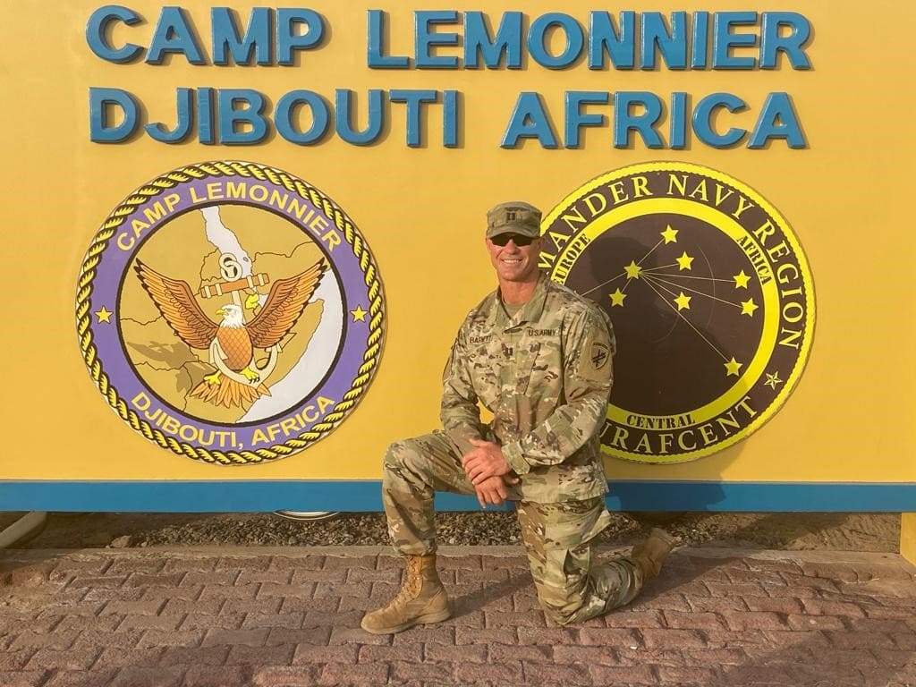 Brian Barnett in front of Camp Lemonnier signage in Djibouti, Africa