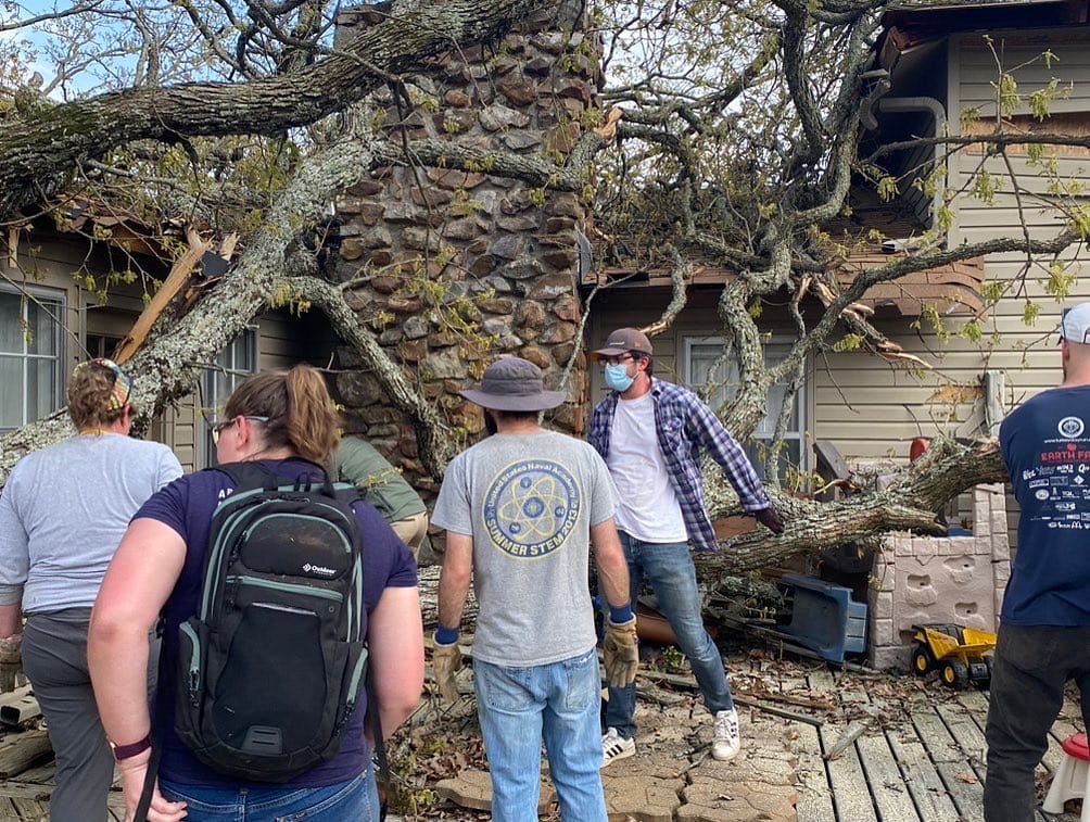 Students working outside a home that was damaged by a falling tree