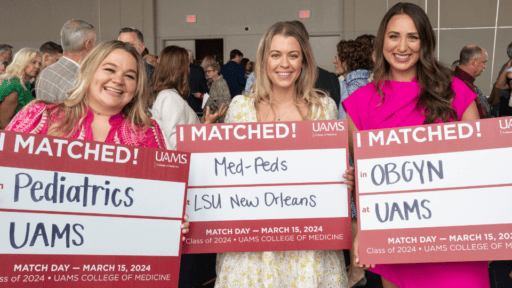 3 students at ceremony holding "I Matched!" signs displaying their residency match locations
