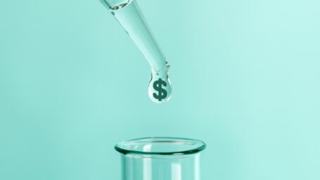 Photo illustration showing pipette with a drop of liquid coming out. There is a dollar sign inside the liquid