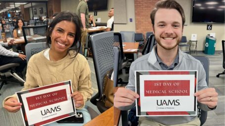 Two UAMS medical students holding up first day of school signs