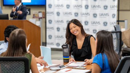 a medical student sitting at a desk talking to other students