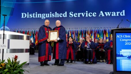 two men in academic robes holding an award plaque