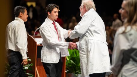 Dean shakes the hand of an M1 student at the white coat ceremony